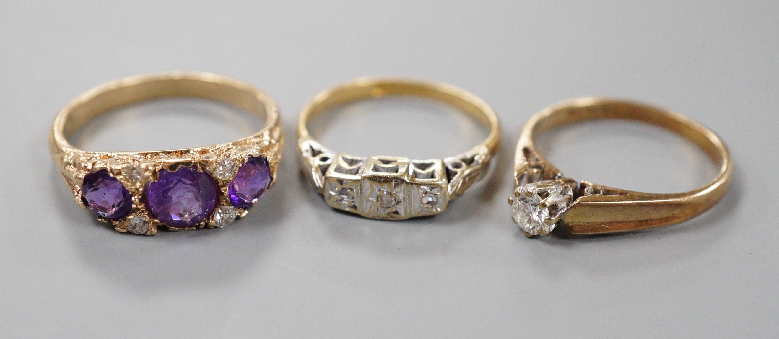 An 18ct and illusion set three stone diamond ring, gross 2.8 grams and two 9ct and gem set rings including amethyst and diamond chip half hoop, gross 5.2 grams.